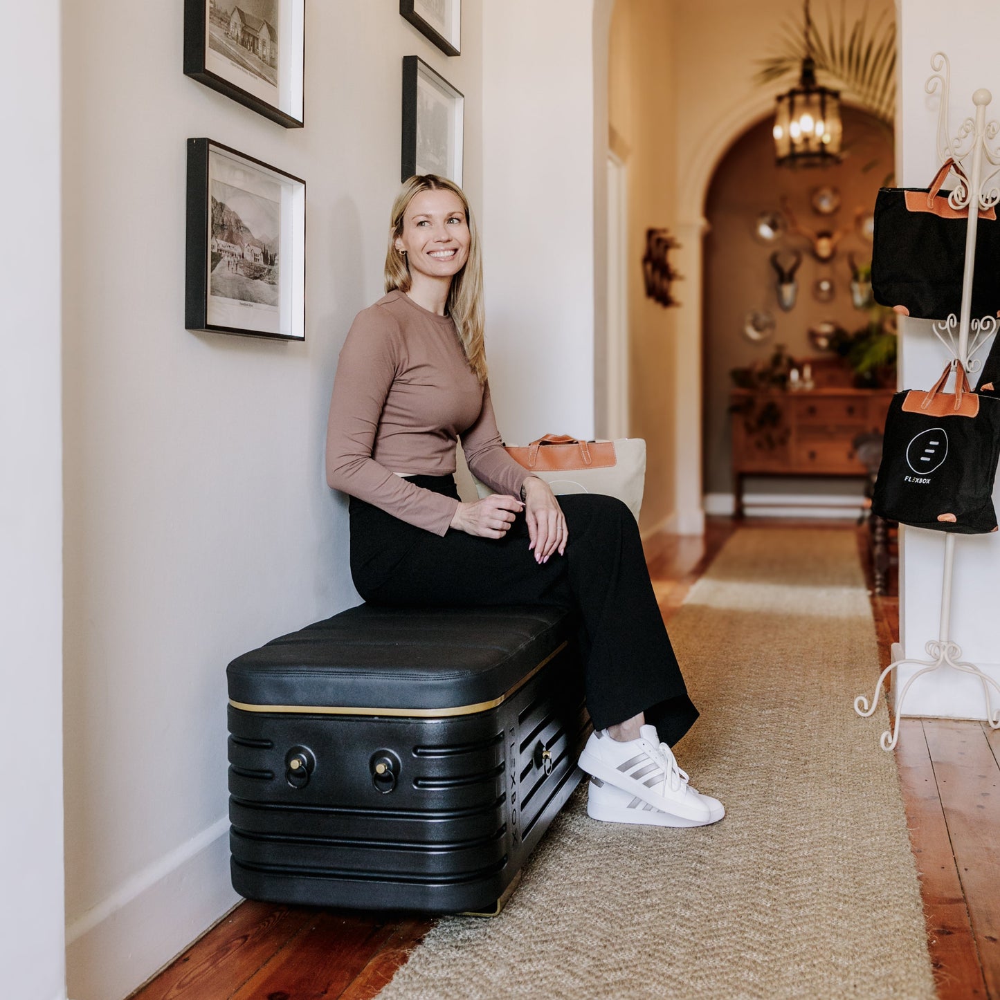 Woman sitting on a black bench in a hallway inside a home