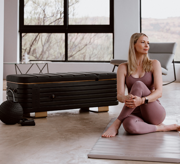 Woman sitting on a yoga mat in a modern room with large windows